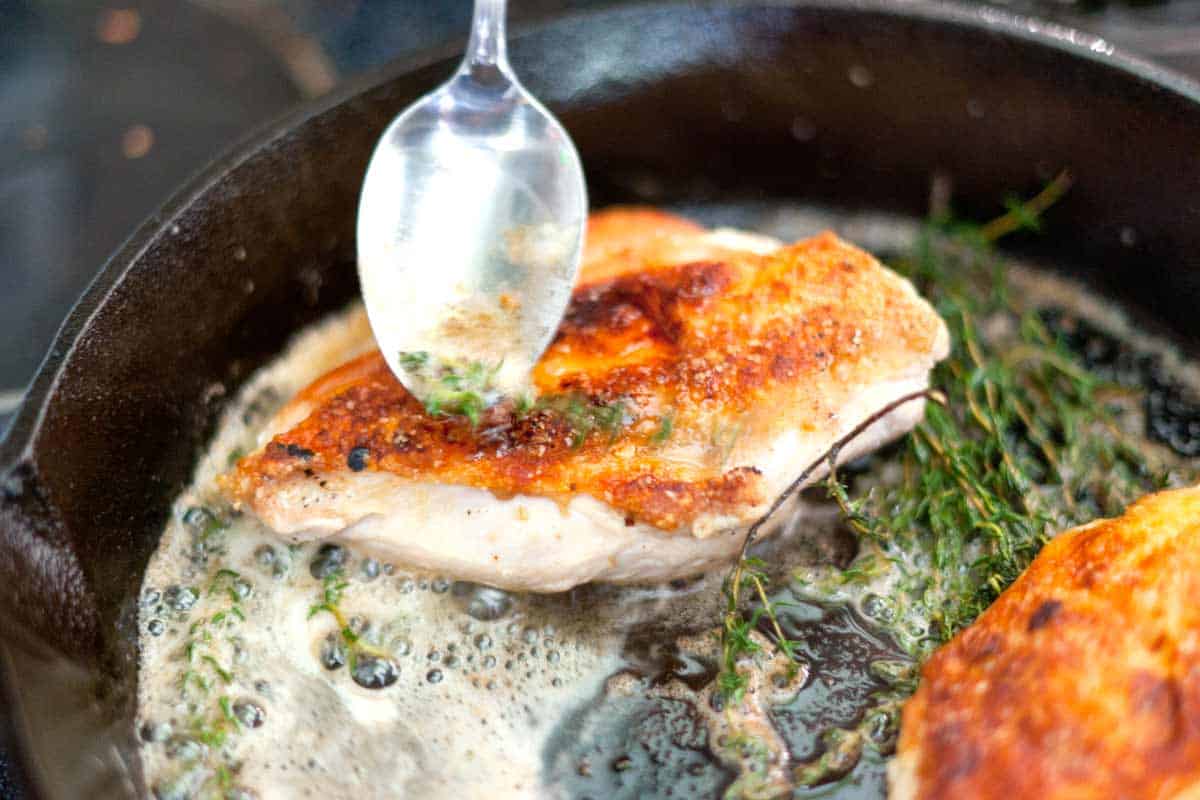 Easy Pan Roasted Chicken Breasts with Thyme Recipe Spooning the thyme butter over the chicken in the pan