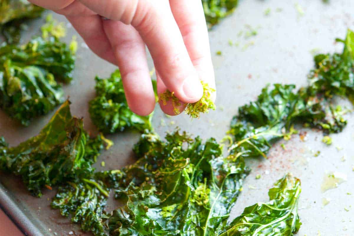 Seasoning baked kale chips with chili and lime