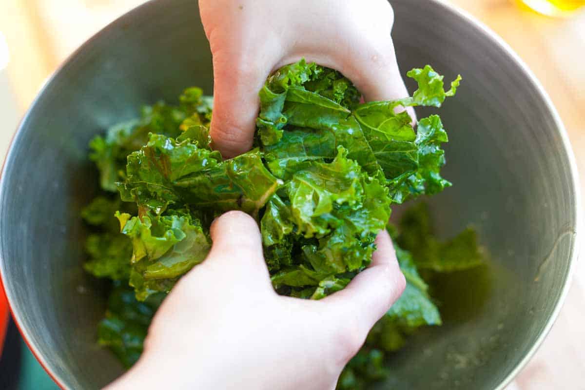 Tossing kale with salt, pepper, and olive oil before baking