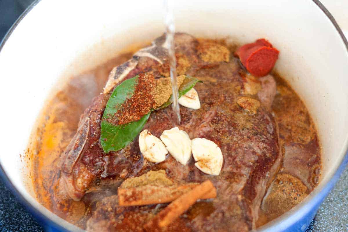 How to Make Irresistible Shredded Beef Tacos Browning chuck roast, then adding spices, garlic, tomato paste, and water