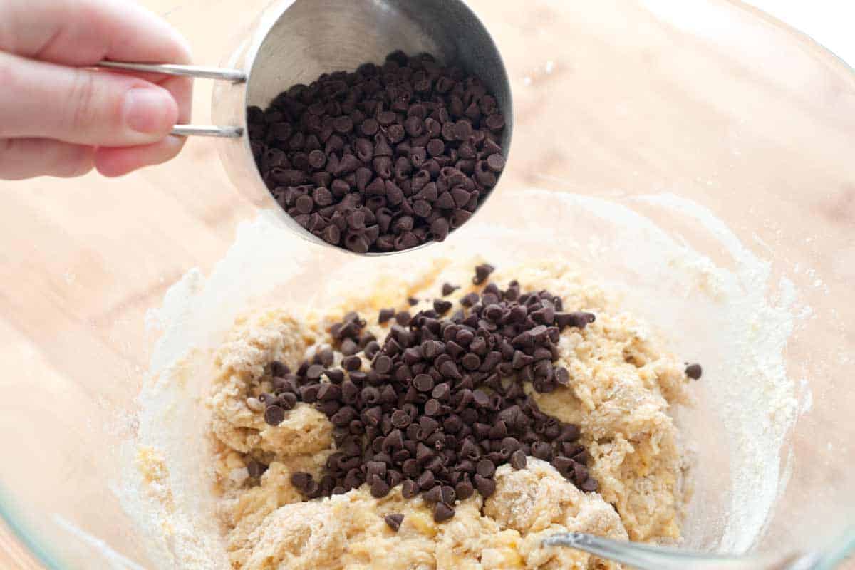 Adding mini chocolate chips to muffin batter for banana muffins