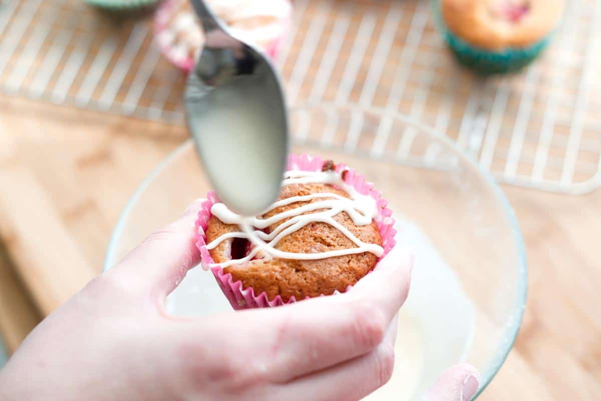 How to Make Strawberry Yogurt Muffins Drizzling the vanilla glaze over a baked and cooled muffin