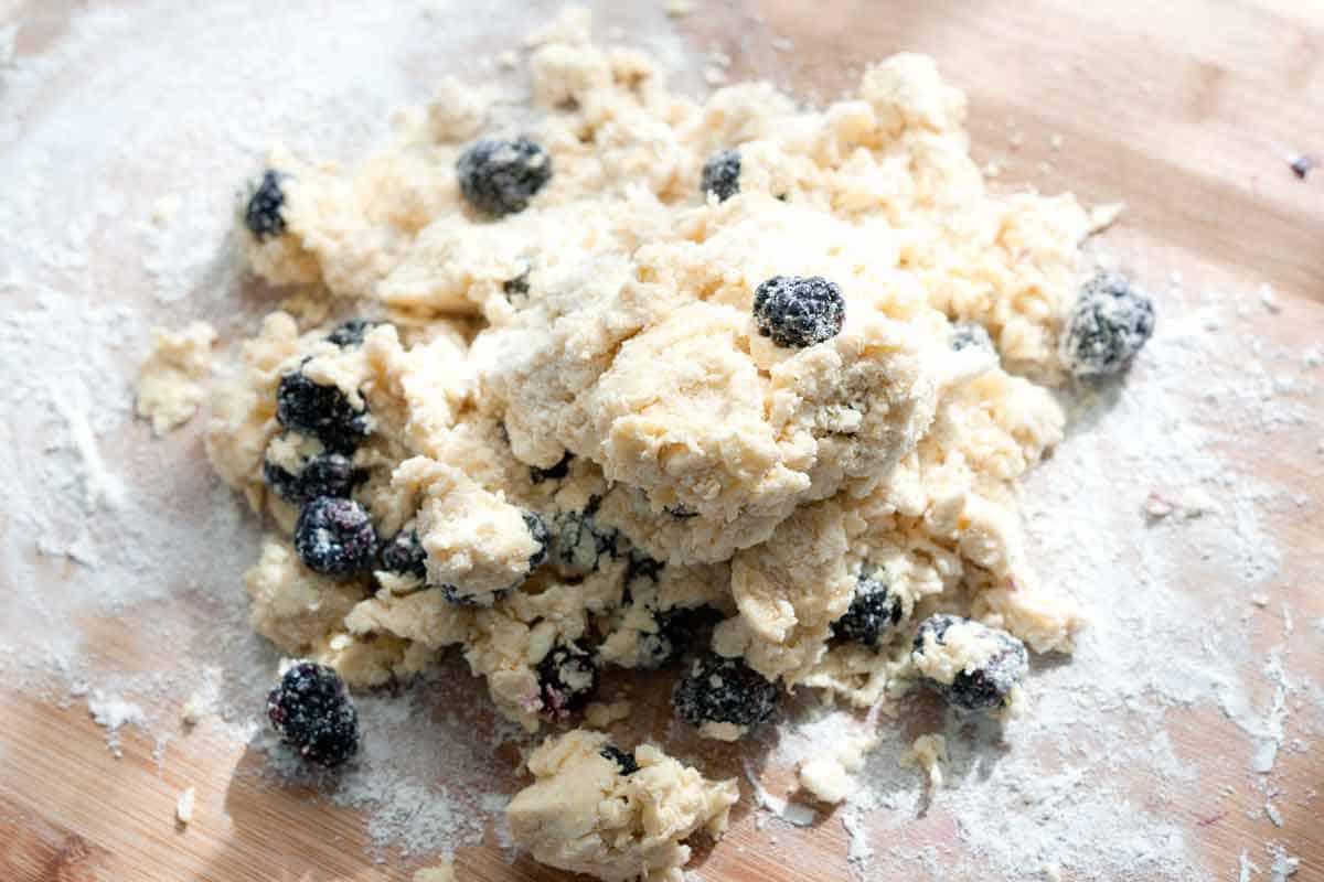 Forming dough with fresh blackberries to make scones.