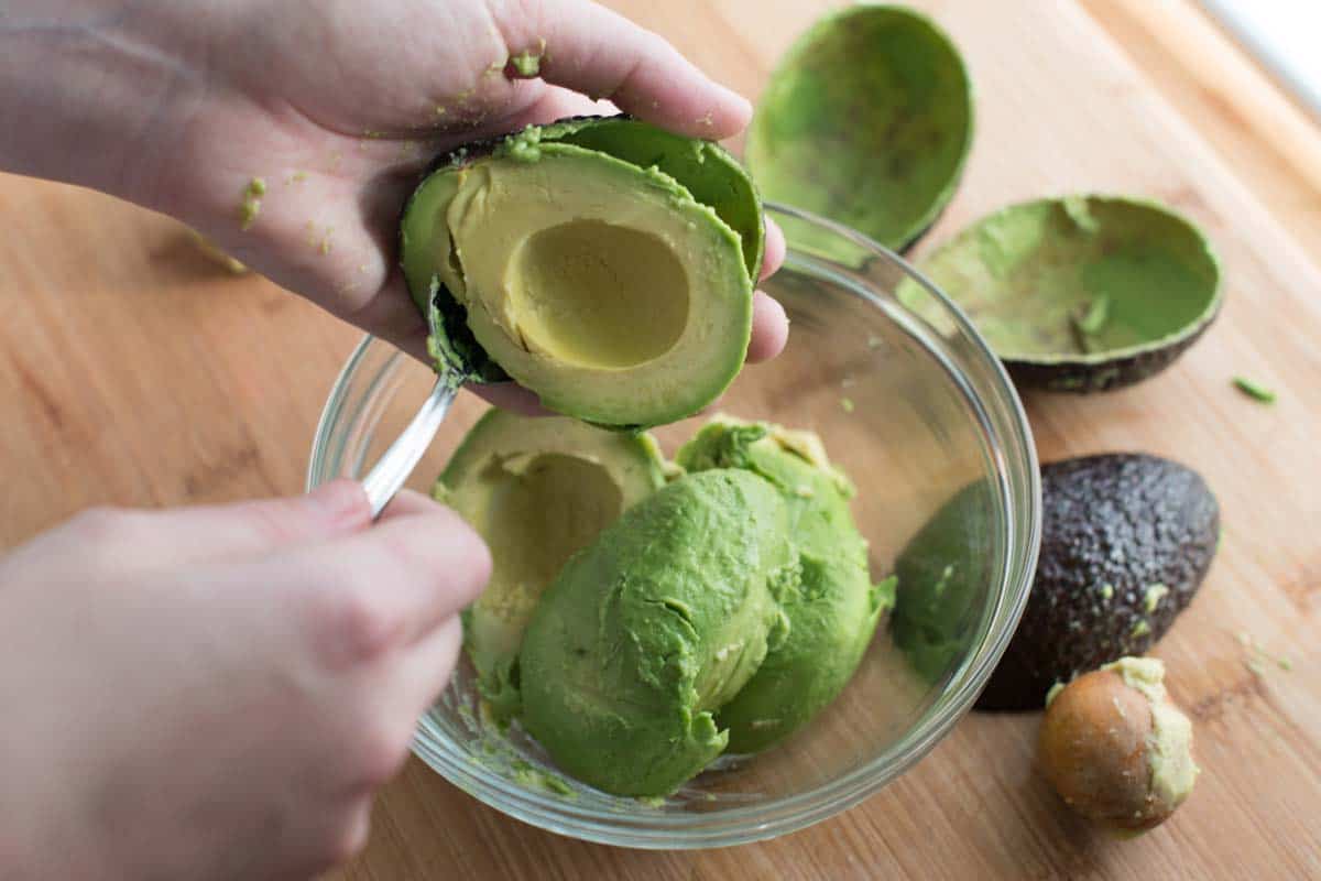 Removing the pit and scooping ripe avocado.