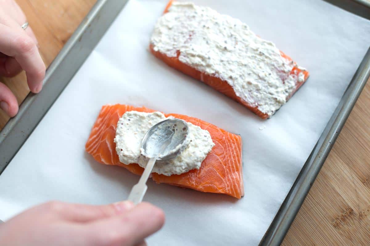 Spreading the sour cream and mustard mixture over salmon fillets