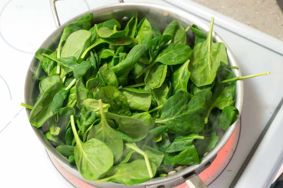Making the lasagna filling with mushrooms, and lots of spinach in a pan.