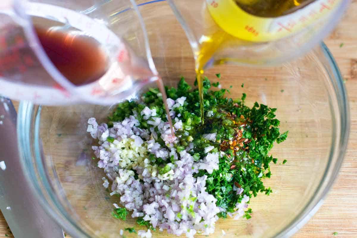 Adding chimichurri ingredients to a bowl