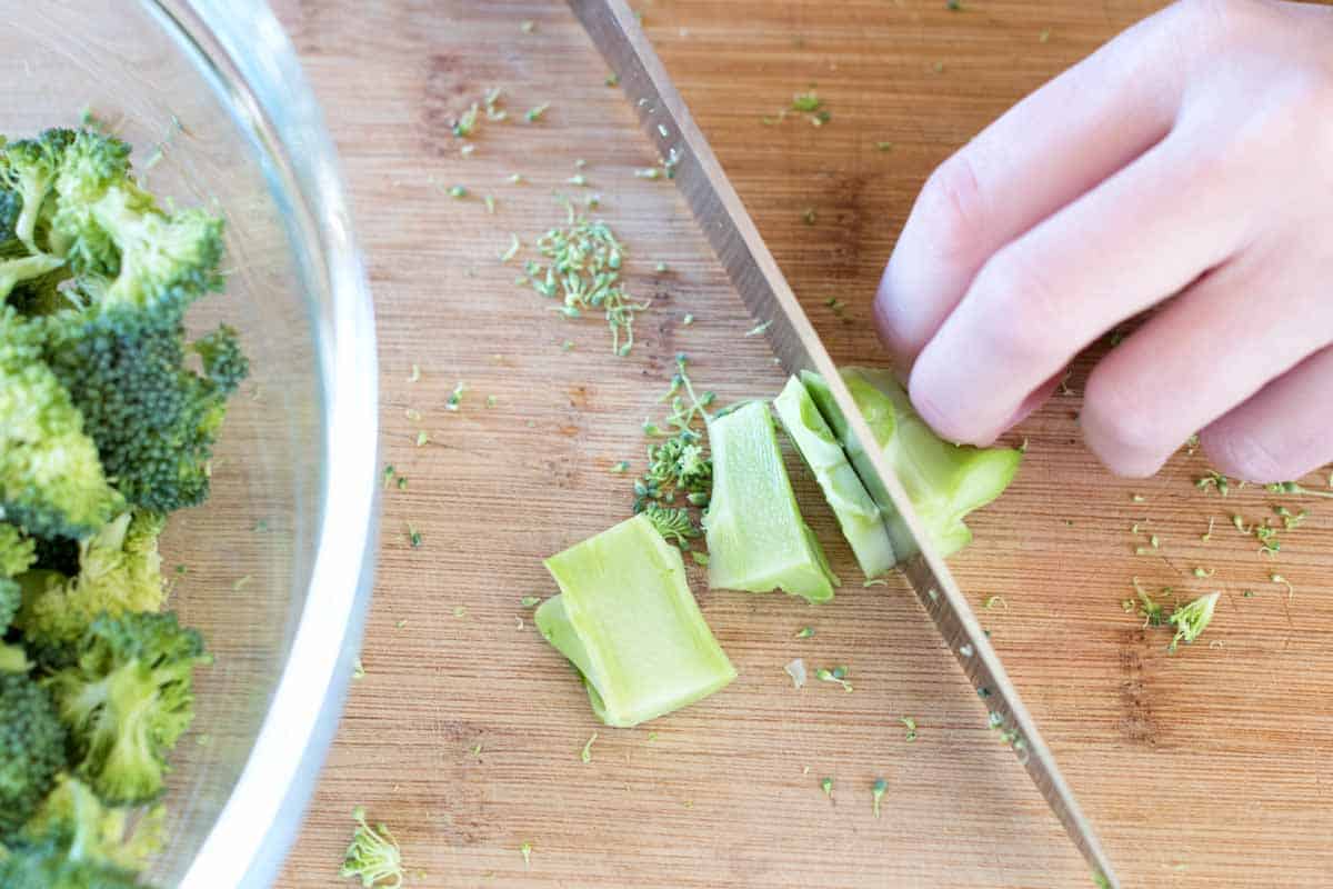 Slicing peeled broccoli stems. Florets are to the side.
