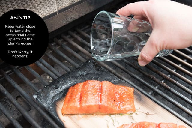 How to Grill Salmon Using a Cedar Plank Cooking salmon on a cedar plank with a glass of water near by for flare ups.
