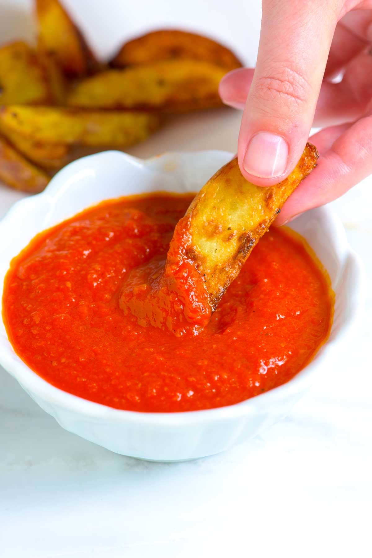 French fry being dipped into homemade ketchup
