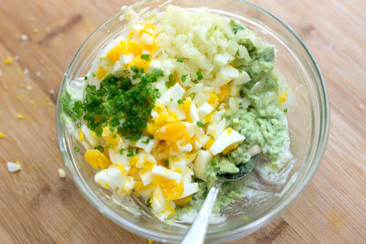 Bowl with hard-boiled eggs, avocado, celery, and fresh herbs