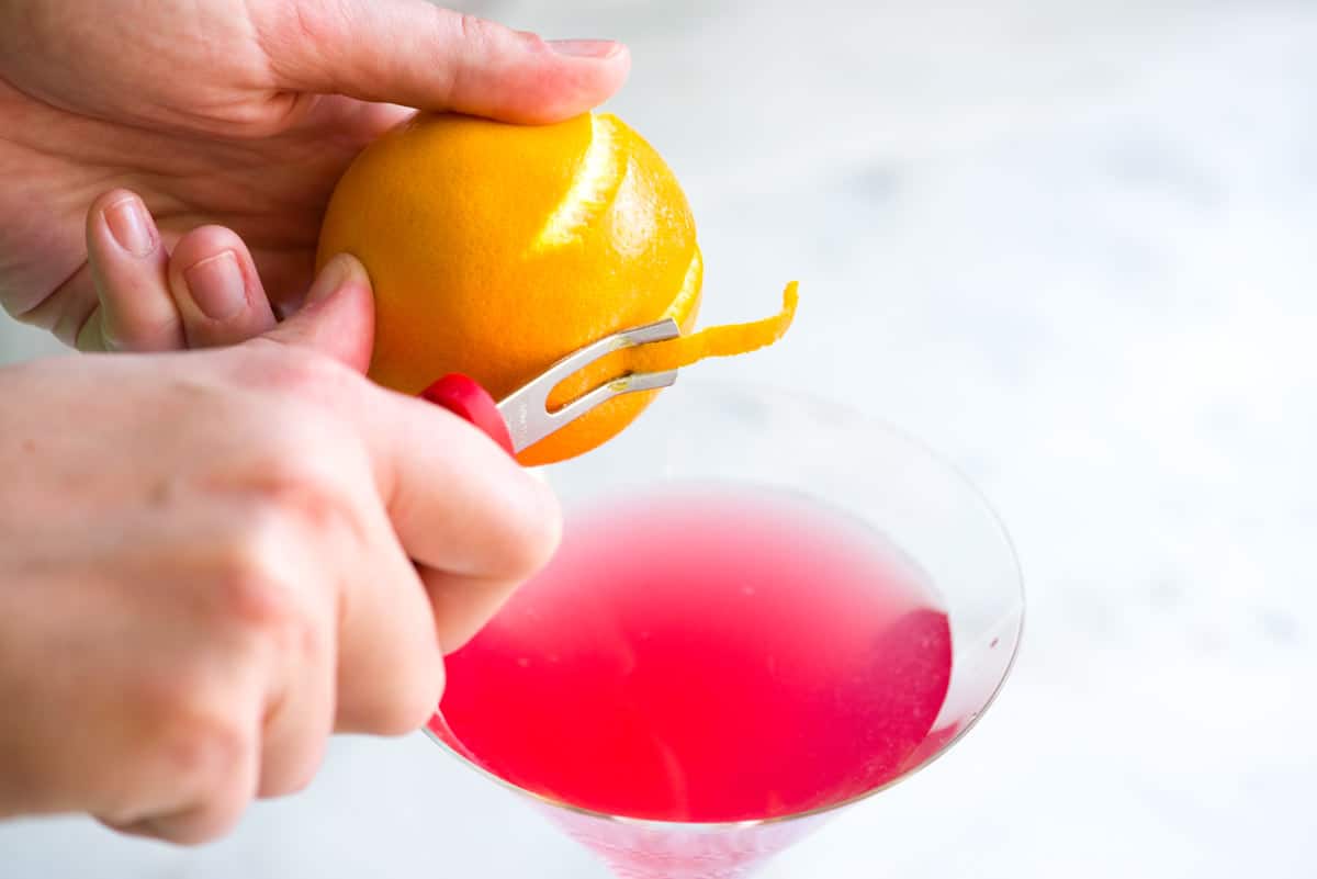 Garnishing a cosmopolitan cocktail with orange peel