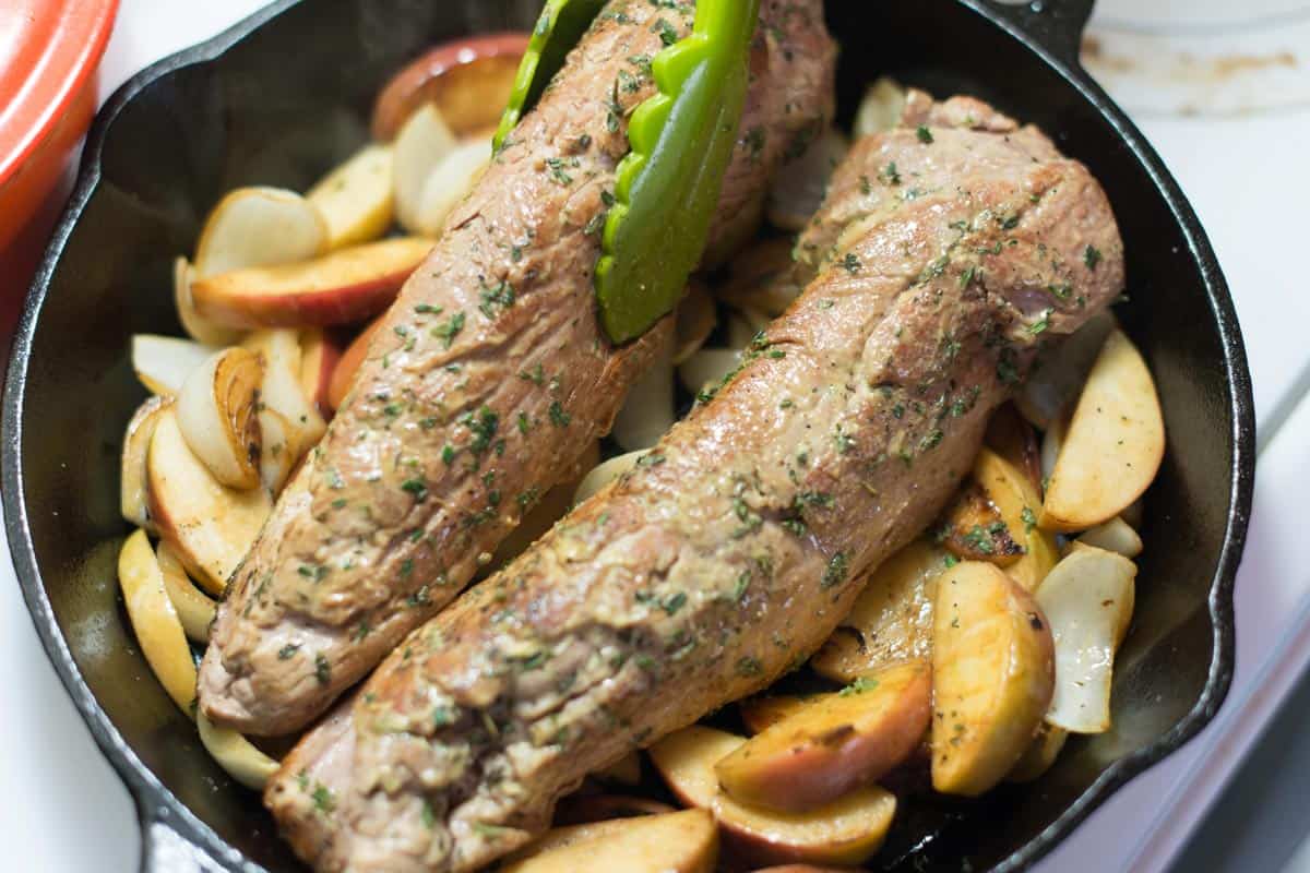 Baking pork tenderloin in cast iron pan on a bed of apples