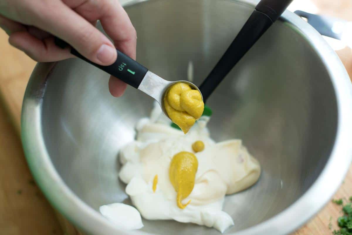 Making potato salad dressing with mayonnaise, sour cream, and yellow mustard