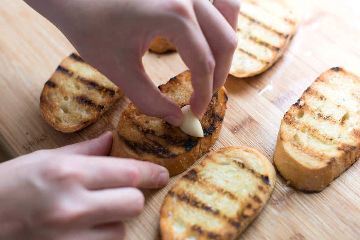 Rubbing toasted bread with a fresh garlic clove.
