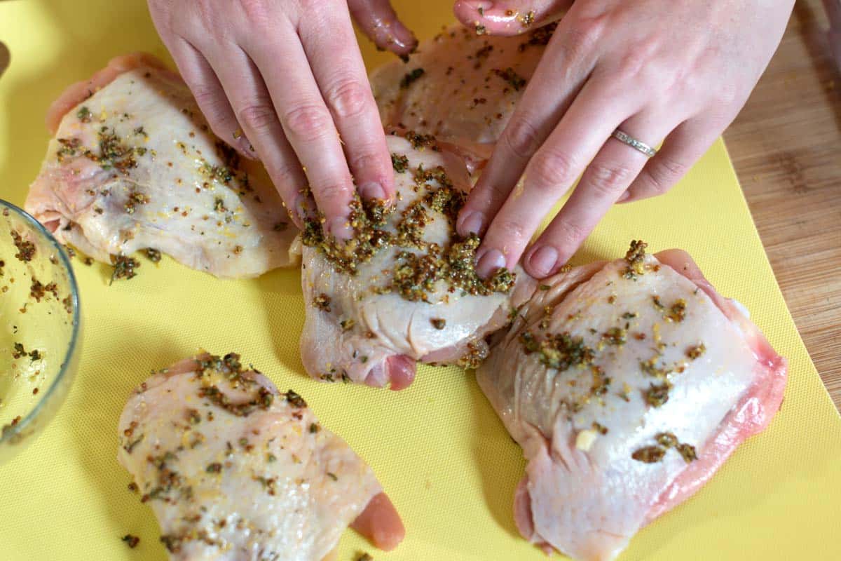 Rubbing chicken thighs with a lemon mustard rub.