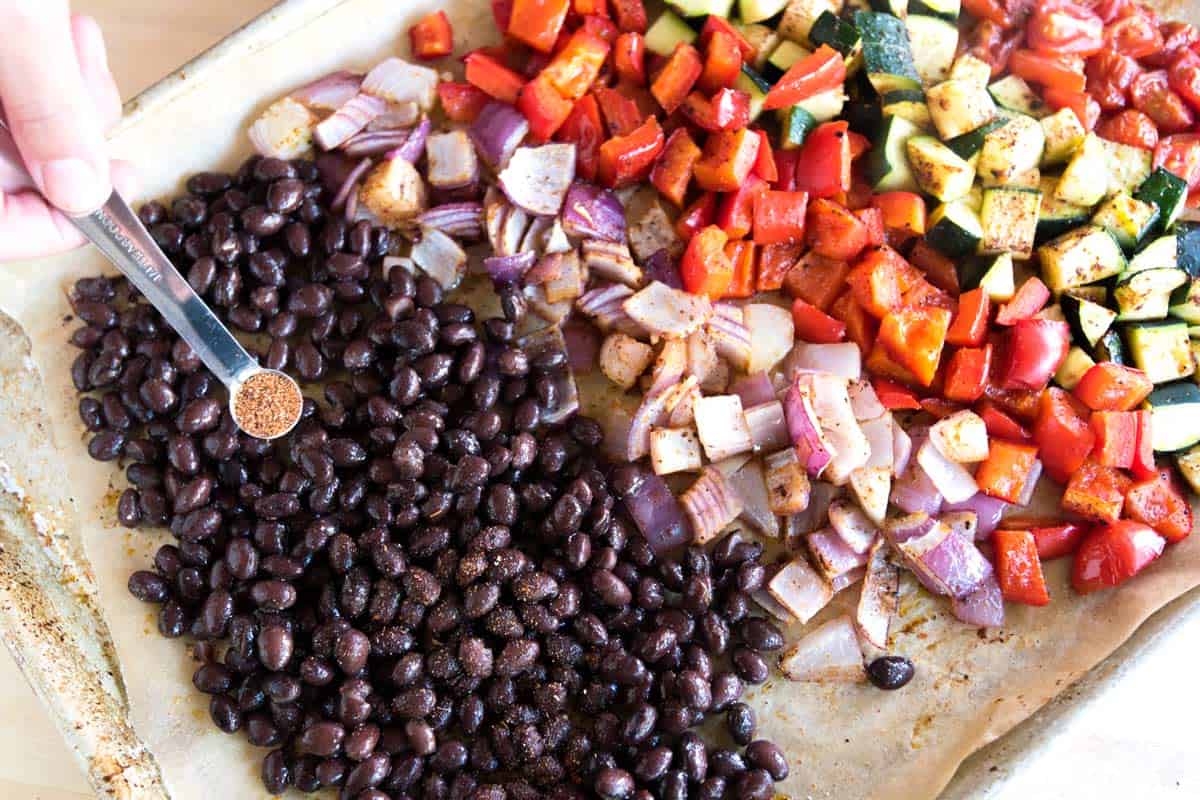 How to Make Veggie Tacos: adding cooked (or canned) black beans tossed with some chili powder to the baking sheet with veggies