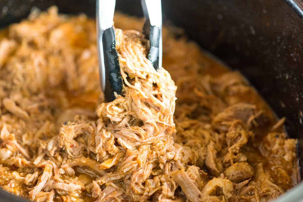 Tender, juicy pulled pork sitting in a slow cooker