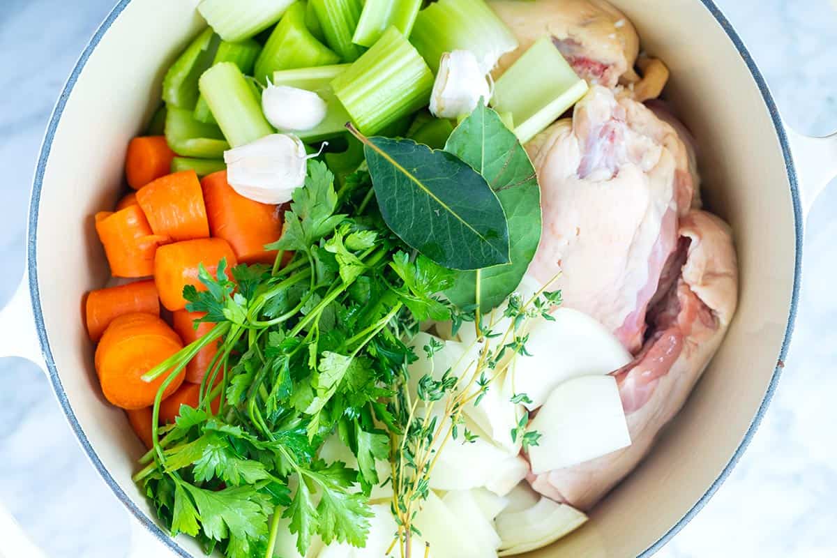 This homemade chicken broth will knock the socks of anything you can buy at the store. Use leftover bones or use chicken parts. Chicken Stock ingredients in a stock pot.