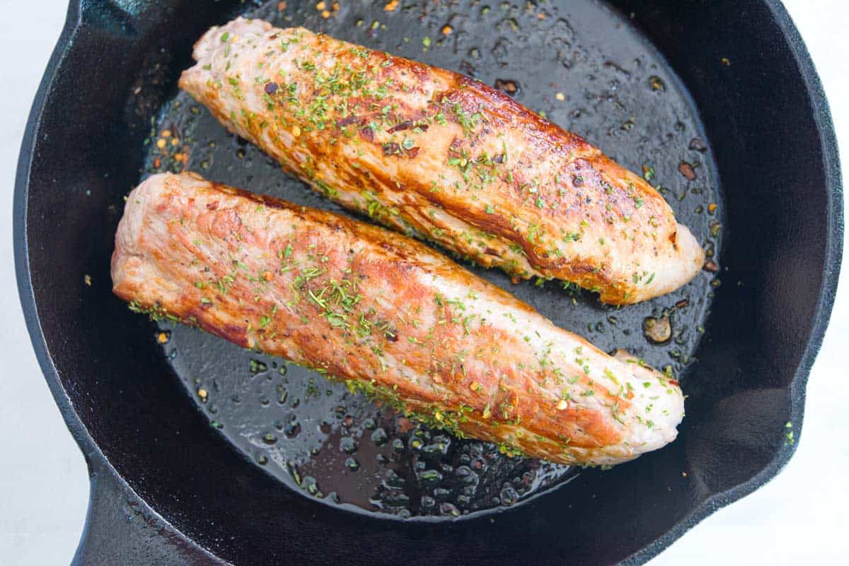 Searing pork tenderloins in a skillet before cooking them in the oven