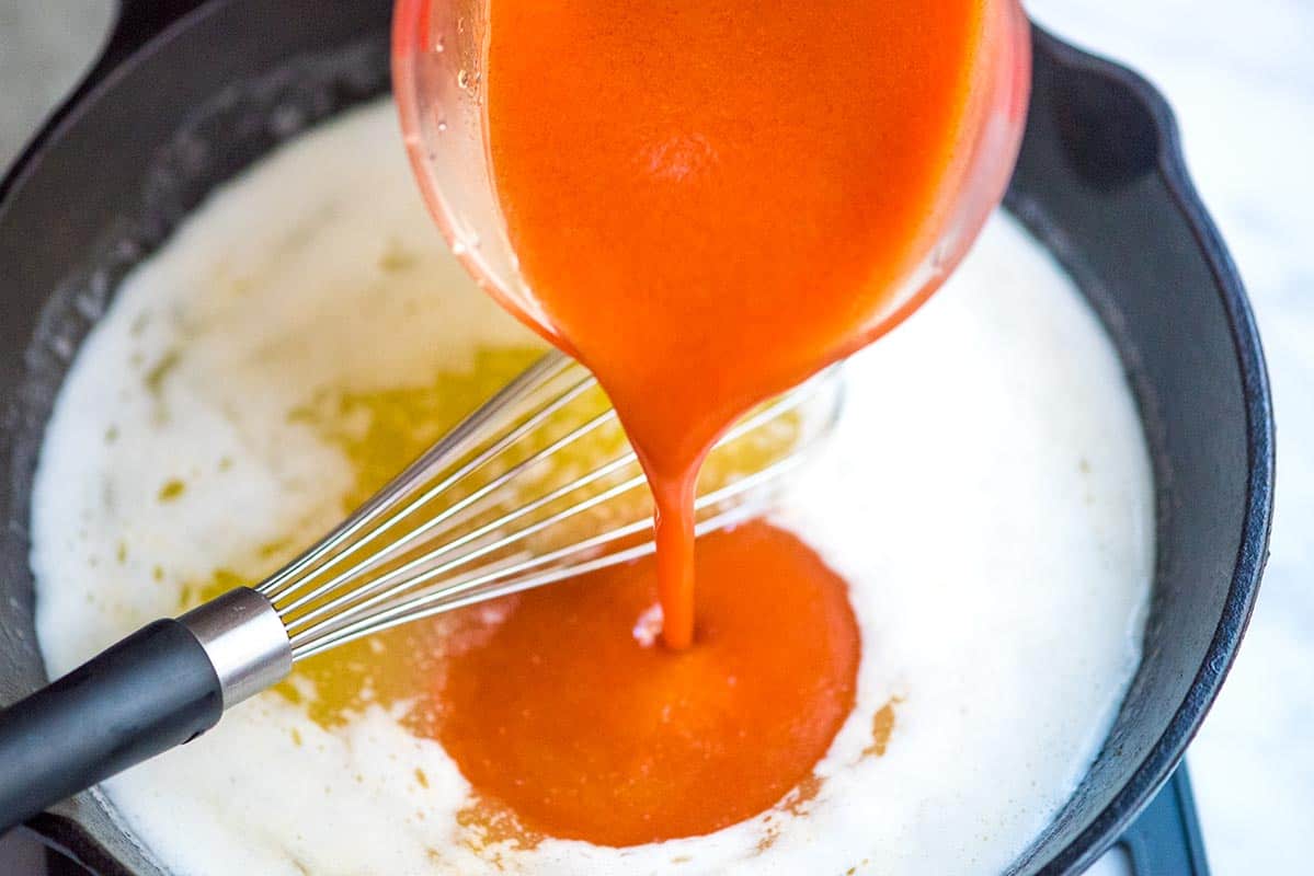 Mixing melted butter with hot sauce and garlic powder.