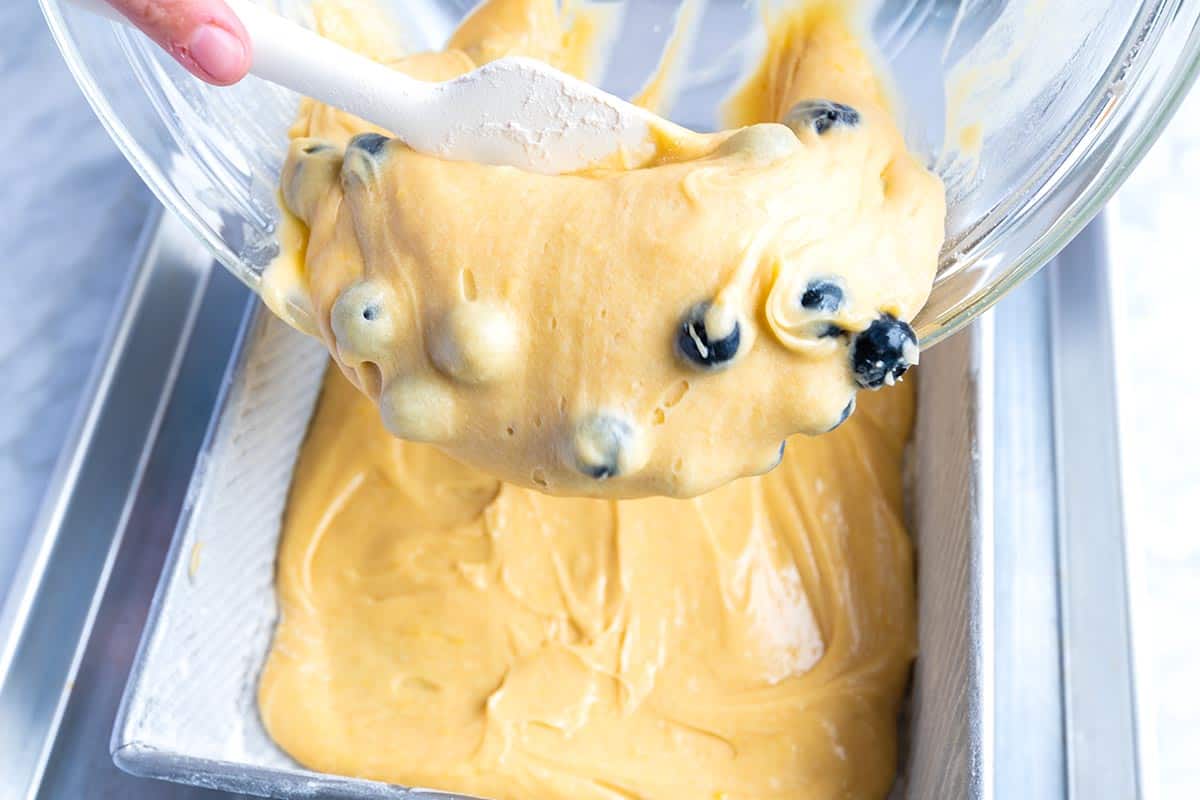 Adding batter mixed with blueberries into baking pan