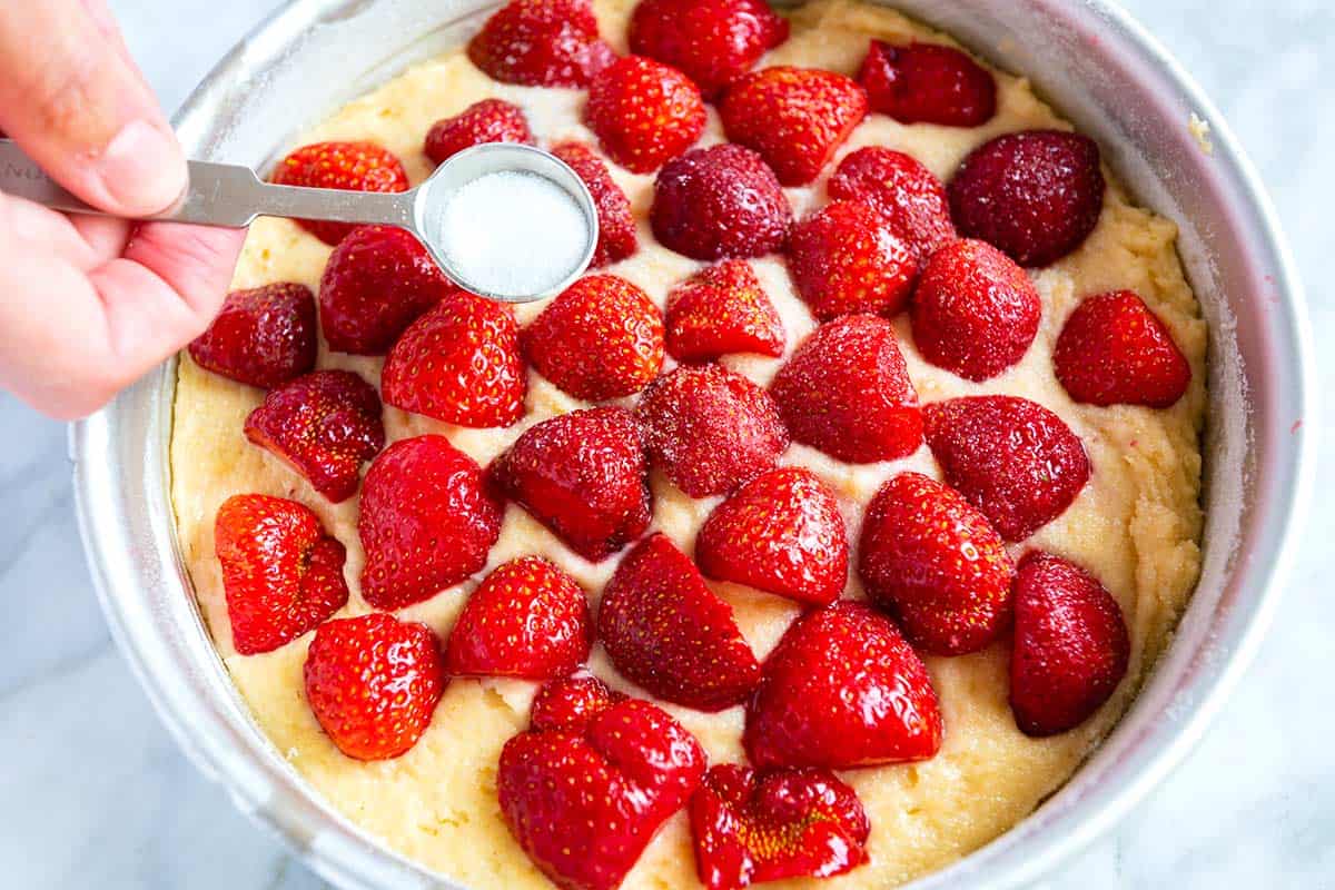 sprinkling sugar over strawberries for fresh Strawberry Cake