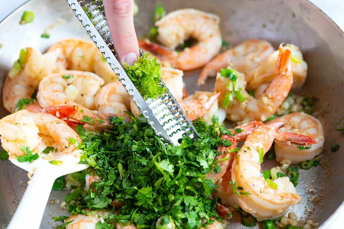 Adding cilantro and the zest and juice of a lime to the shrimp