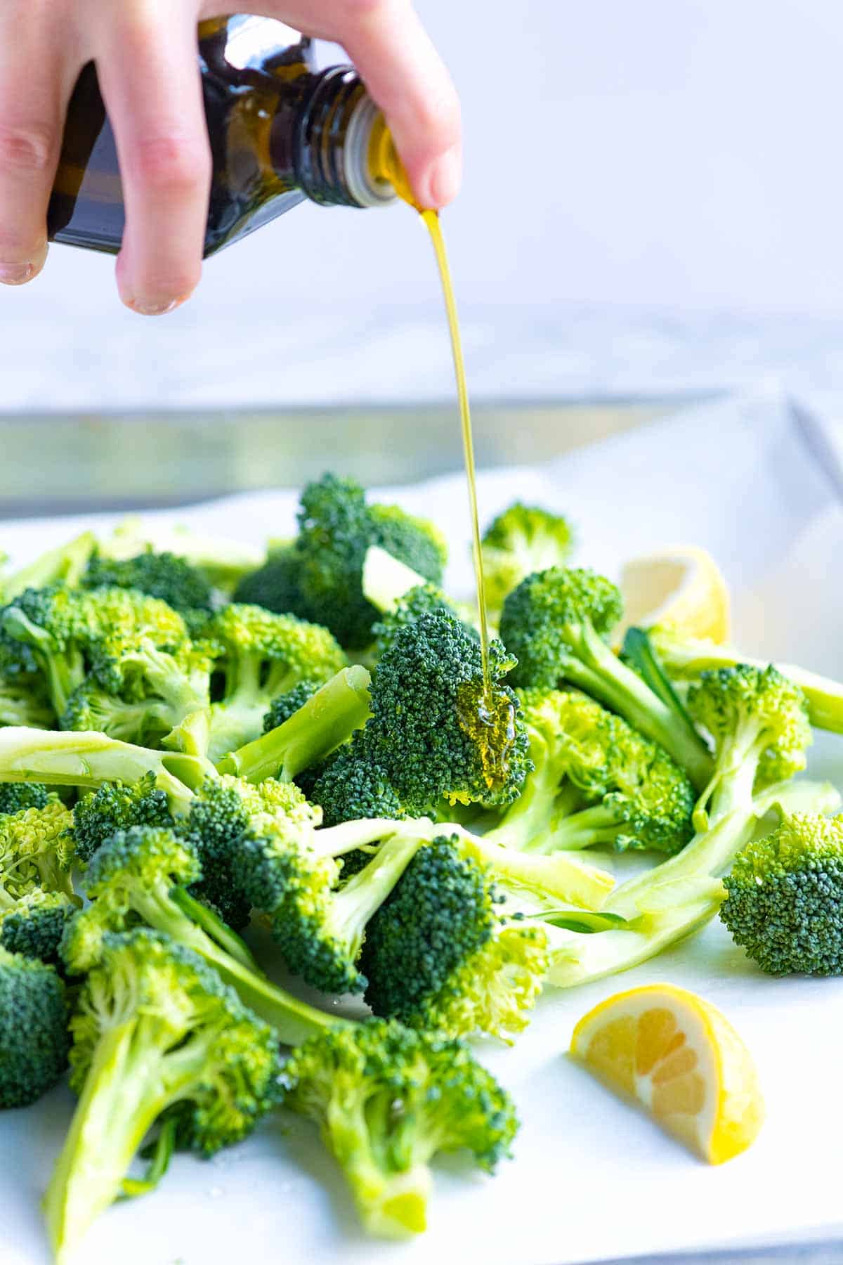 Adding olive oil to raw broccoli before roasting in the oven