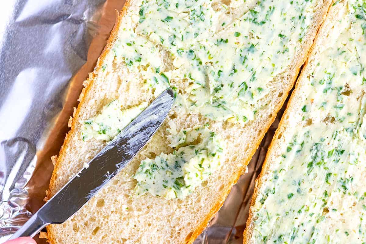Spreading garlic butter over bread before baking in the oven