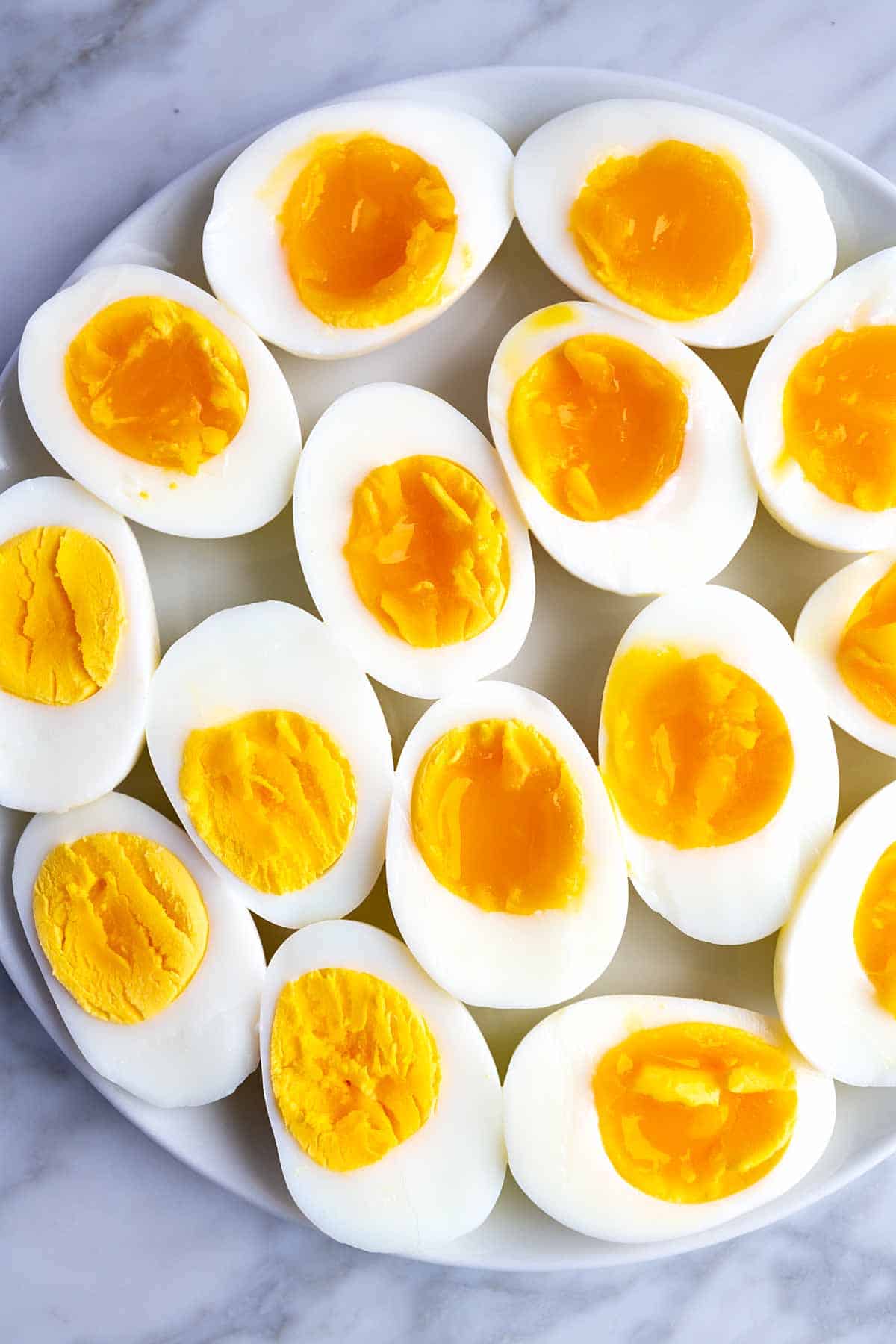 Instant Pot hard-boiled eggs and soft-boiled eggs cut in half on a plate