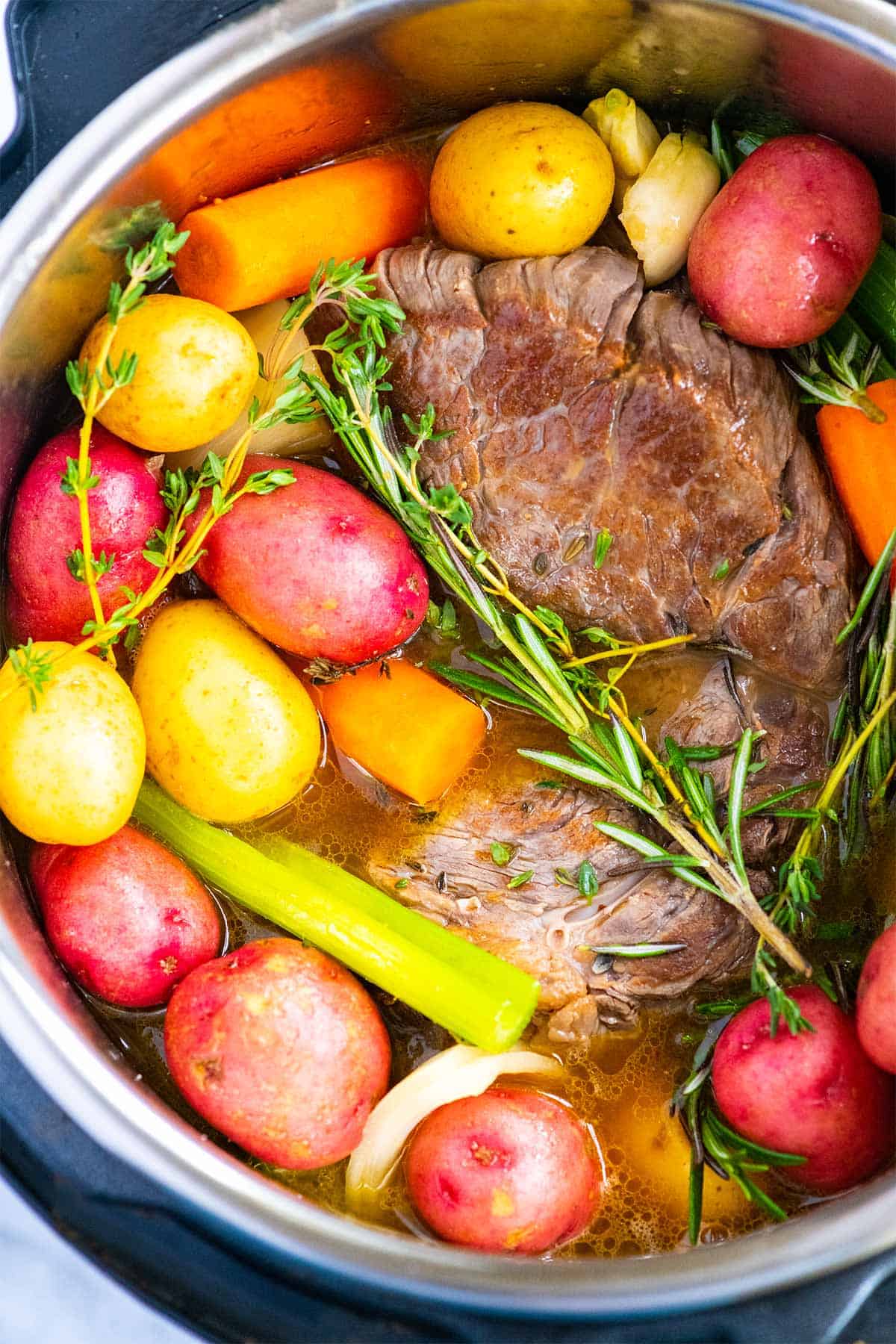 Seared chuck roast with rosemary, thyme, and carrots ready for the Instant Pot
