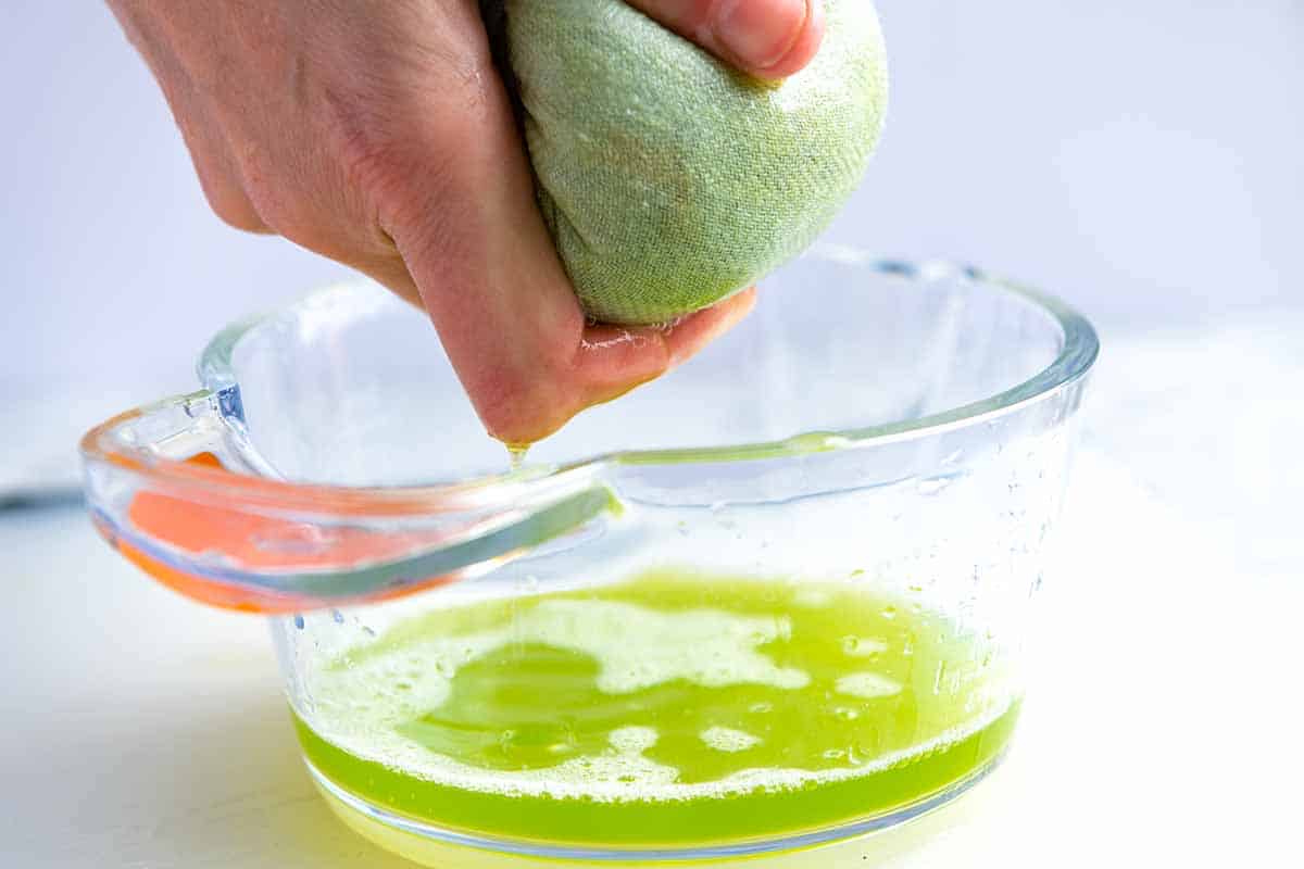 Squeezing salted cucumber in cheese cloth to remove excess water for the best tzatziki