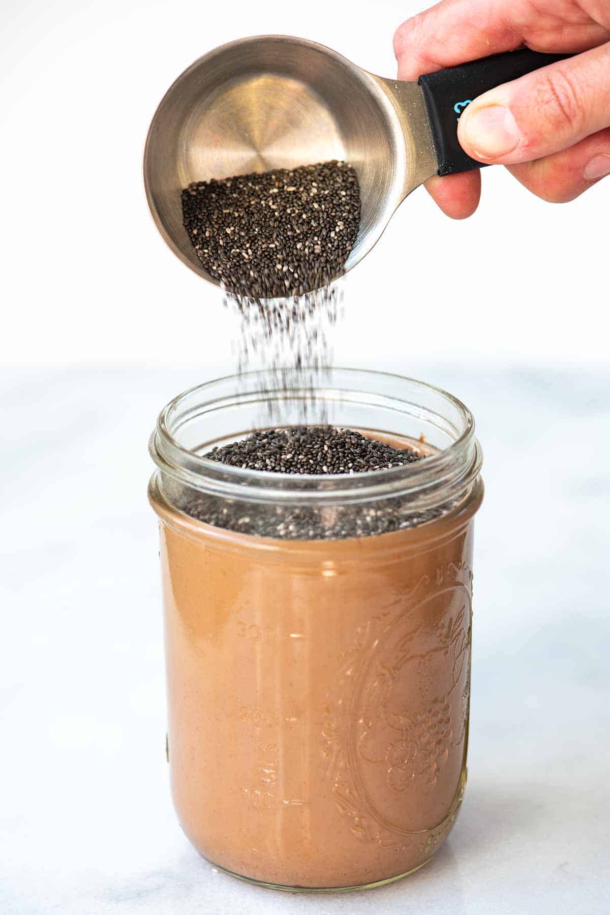 Adding chia seeds to the chocolate milk mixture for chocolate chia pudding