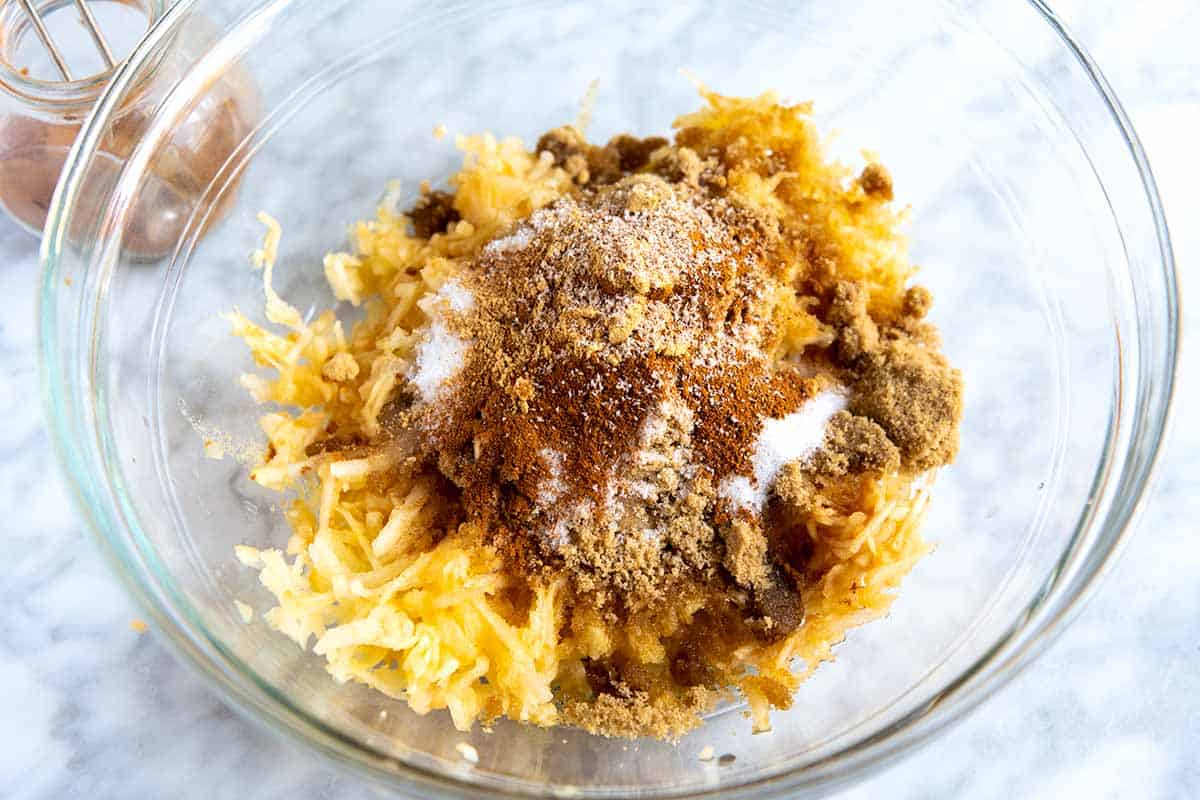 A bowl with shredded apple, sugar and spices.