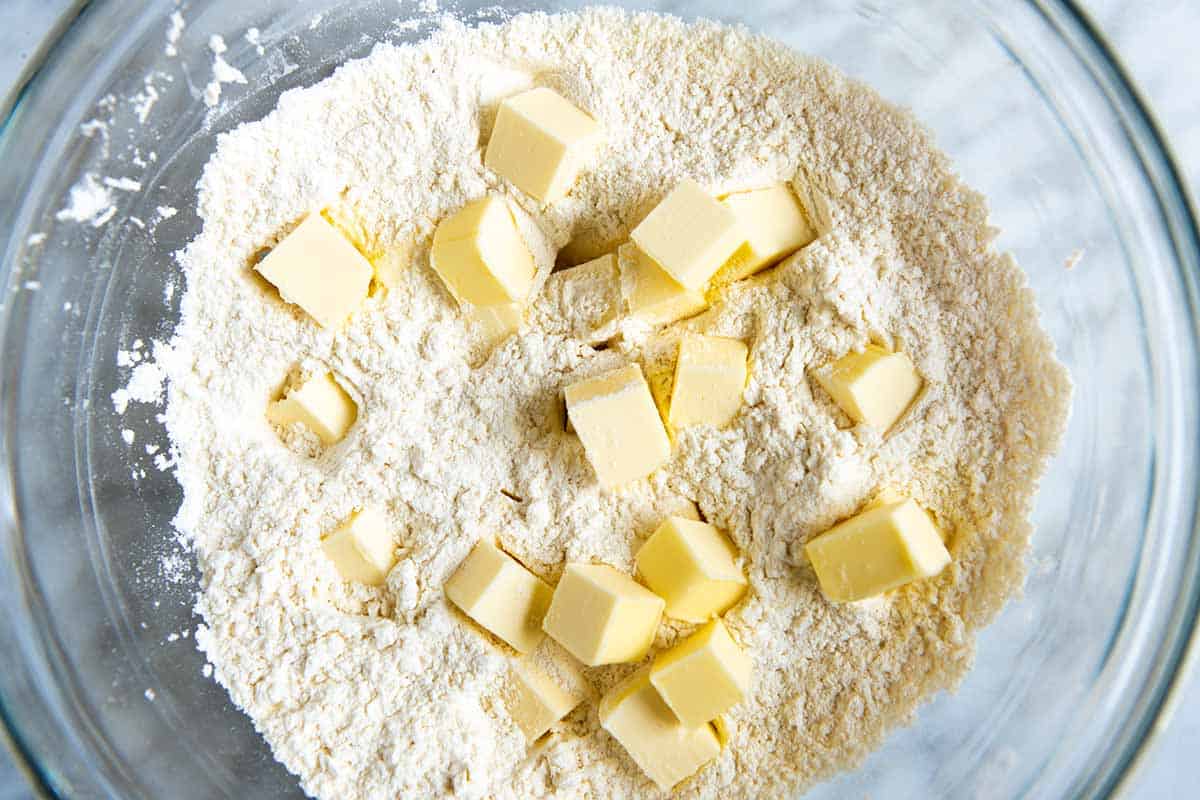 Adding cold butter to flour to make drop biscuits.