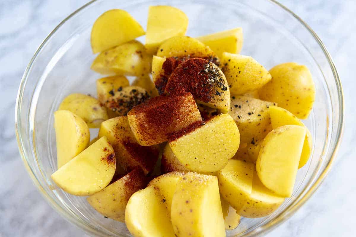 Seasoning potatoes before they go into the oven for roasting