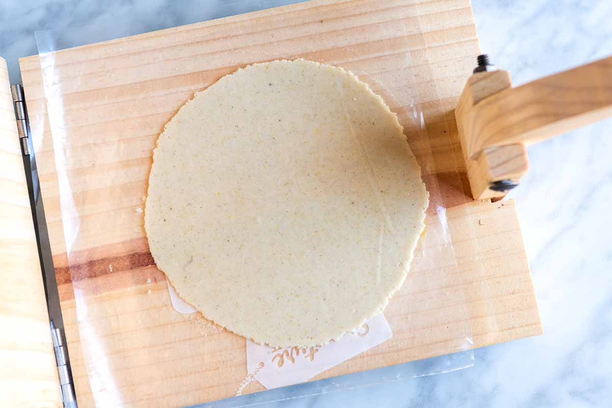 Pressing corn tortillas using a tortilla press, step 3 (showing a flattened perfectly round tortilla).