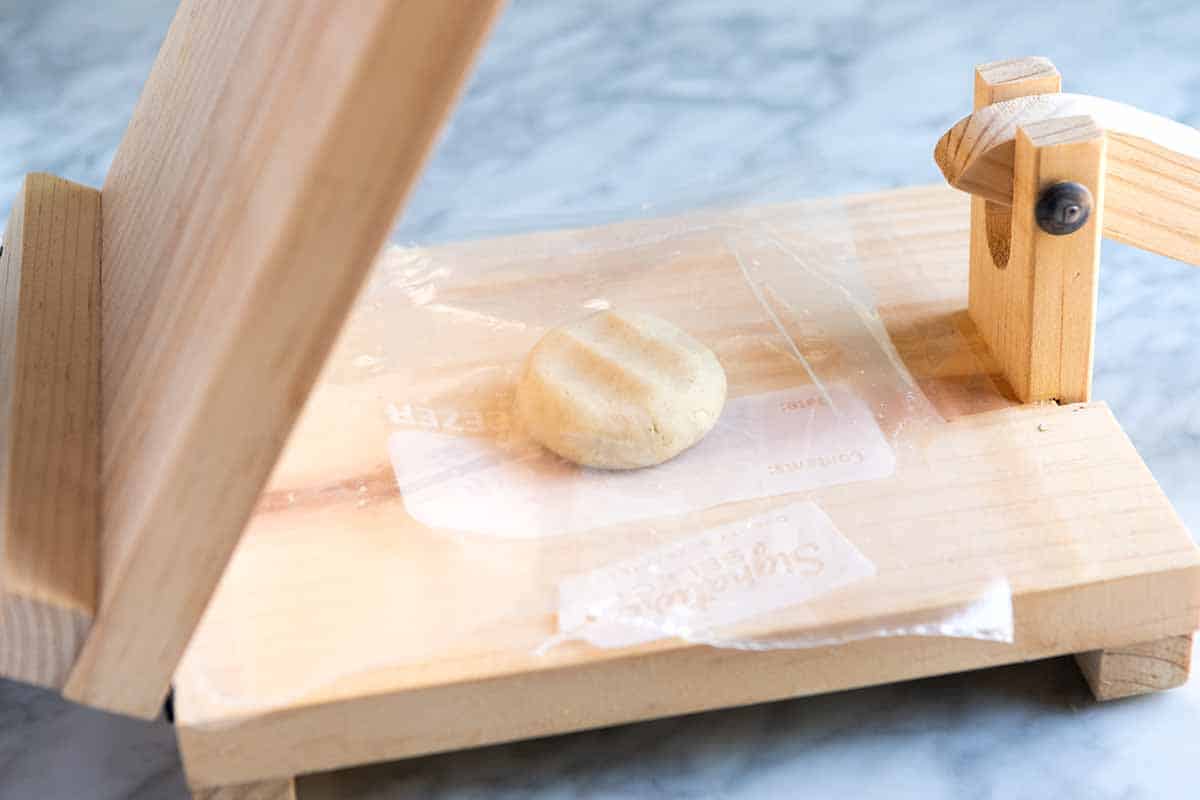 Pressing corn tortilla dough into tortillas, step 1 (add ball of dough to the middle of the press).