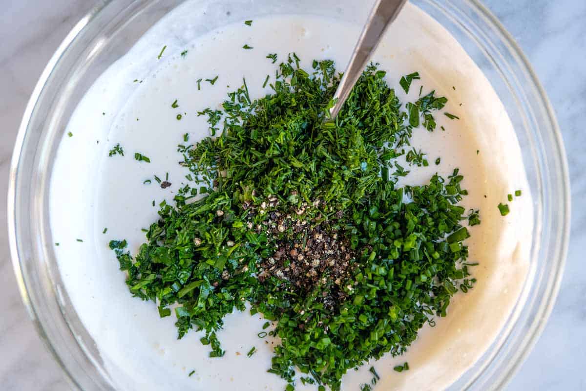 Mixing ranch dressing ingredients together with fresh herbs