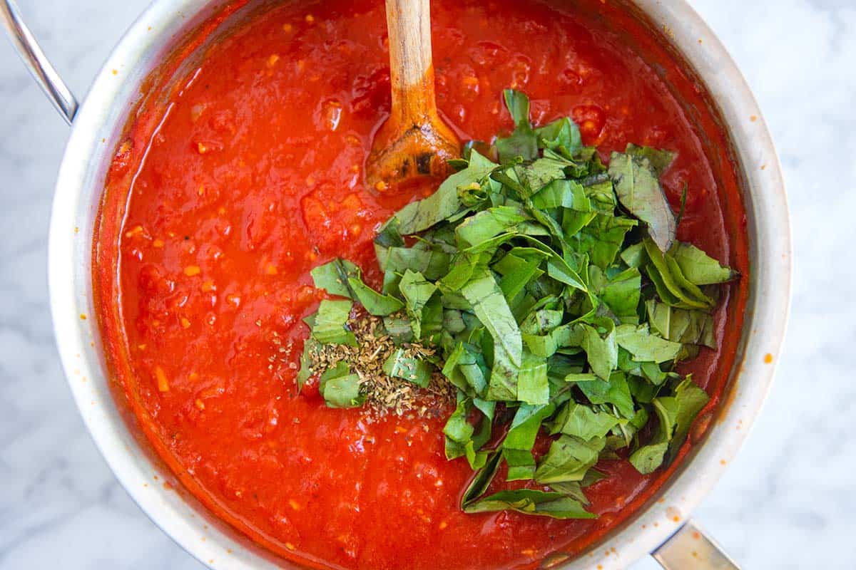 Stirring fresh basil into red pasta sauce