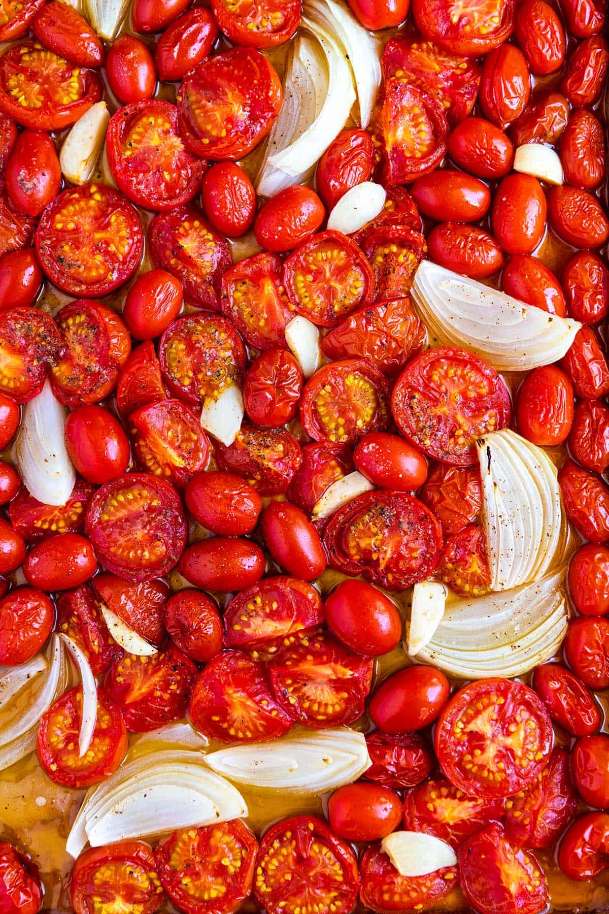 Baking sheet of roasted tomatoes, onion, and garlic.