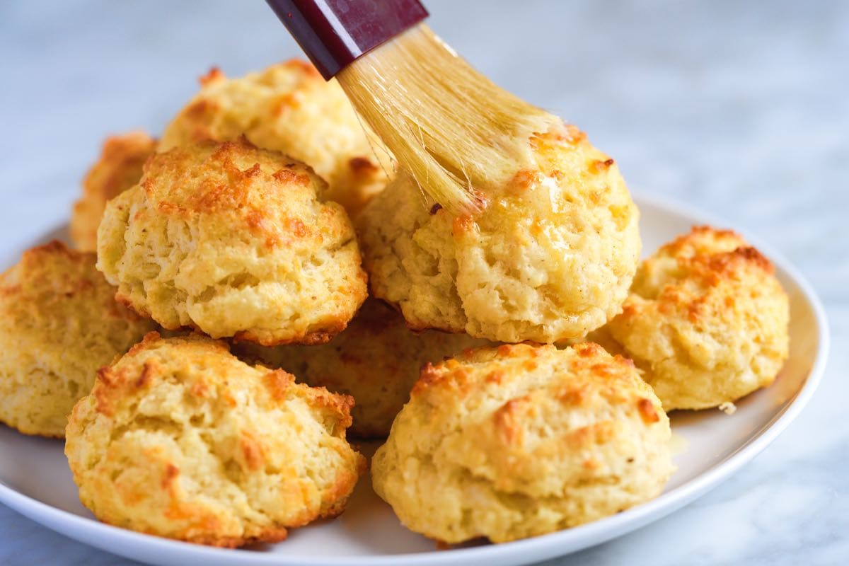 Brushing butter on top of the cheese biscuits