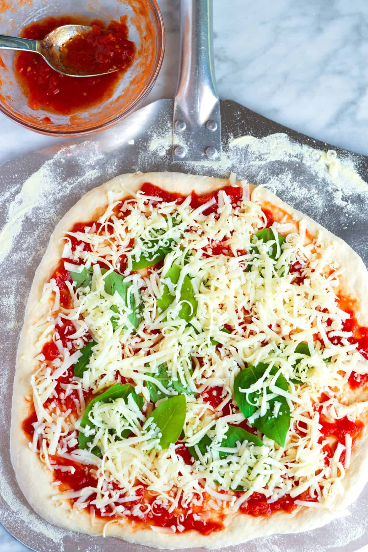 Assembling margherita pizza with an authentic fresh tomato sauce and mozzarella cheese