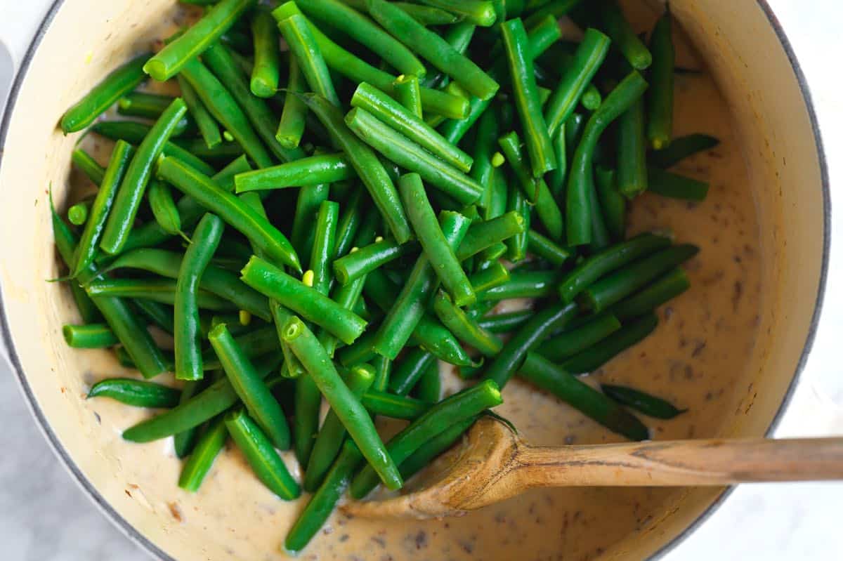 Stirring the blanched green beans into the creamy sauce before baking the casserole