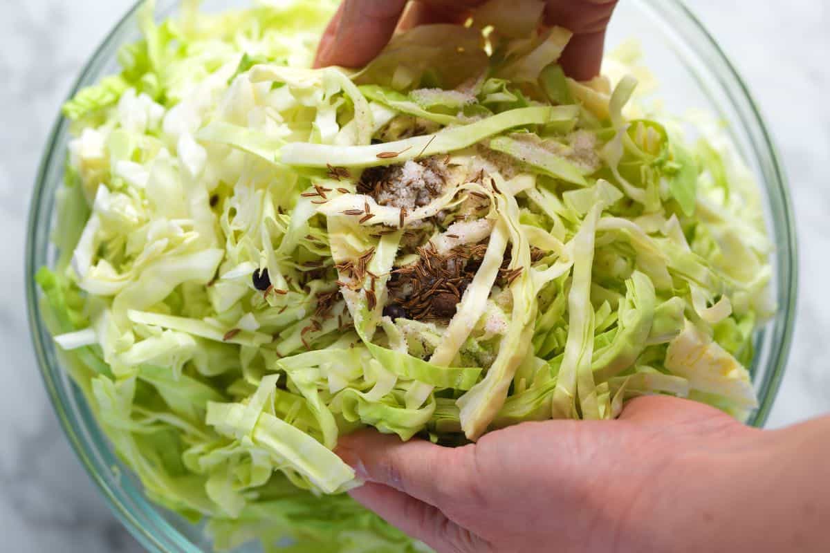 Tossing sliced green cabbage with salt and spices