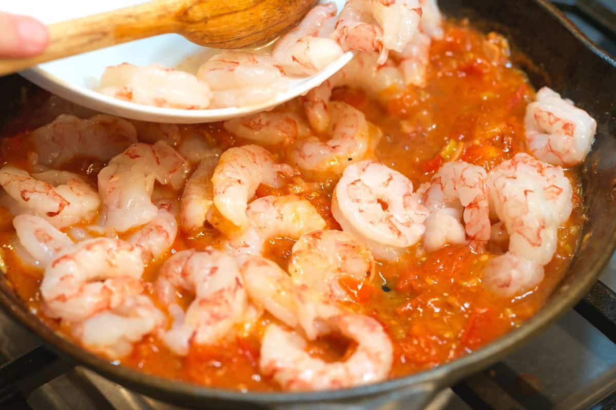 Adding shrimp to the sauce so they gently cook before serving over grits.