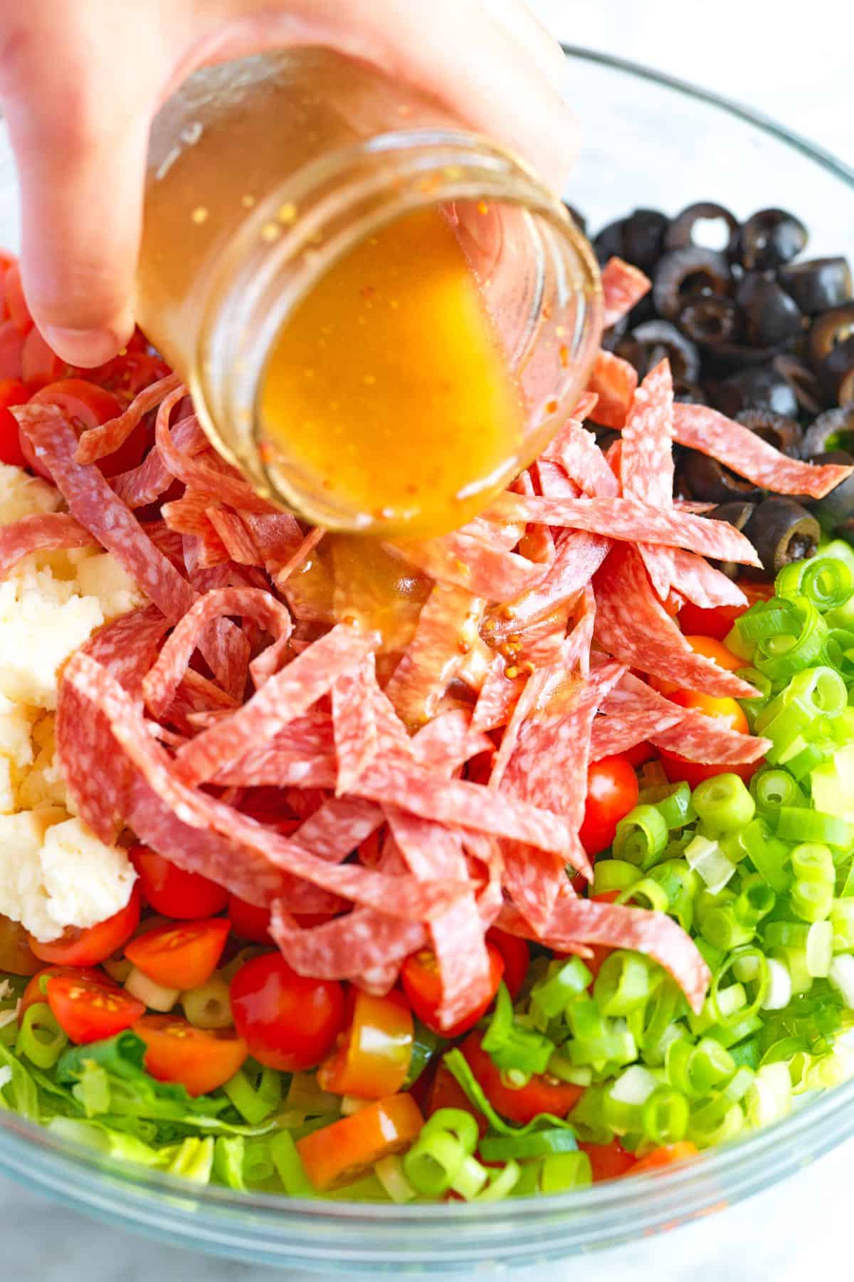 Pouring the red wine vinegar salad dressing over our chopped salad.
