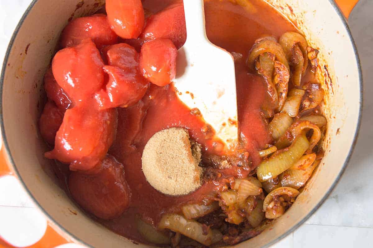 Ketchup ingredients including onions, spices, brown sugar and canned tomatoes ready to be simmered into a thick, shiny sauce