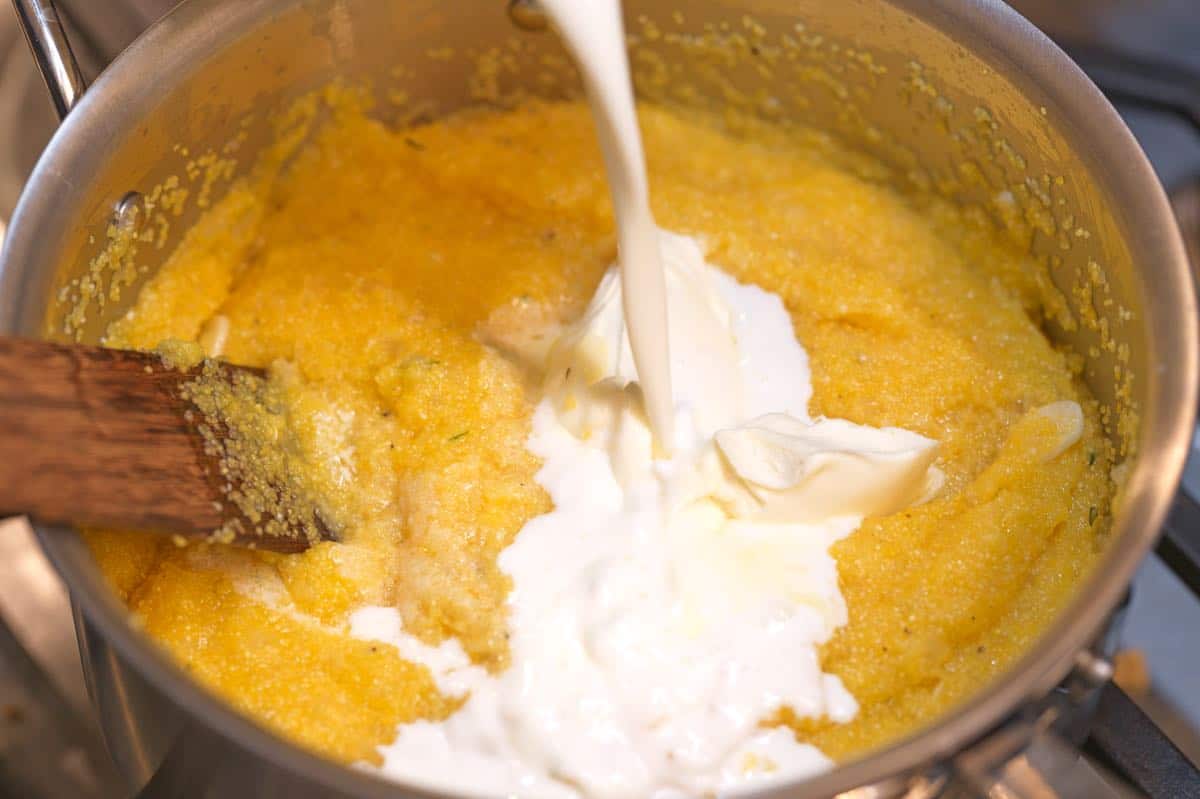 Making the polenta creamy by stirring in milk and mascarpone cheese